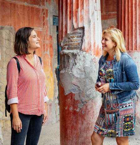 A local and tourist standing at two pillars in Pompeii