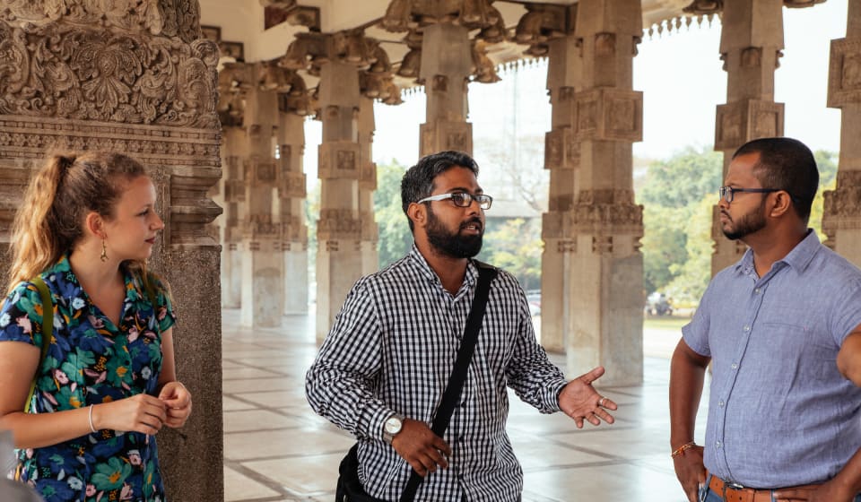A local guide telling a story to a group of tourists in Sri Lankan temple