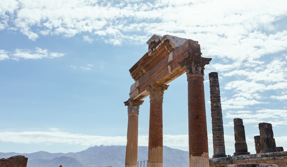 An ancient Roman pillars with Mount Vesuvius in the background