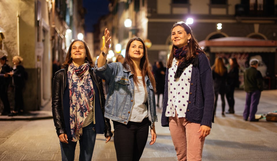 A local guide having two tourists on a private tour in the evening at the streets of Florence