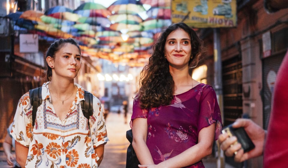 A local and a tourist near the Grand Bazaar in a street with colorful umbrellas hanging in the streets in Istanbul