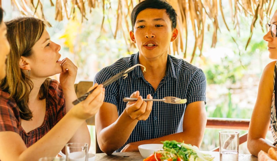 A local guide explaining a story with some tourists while sharing Vietnamese food