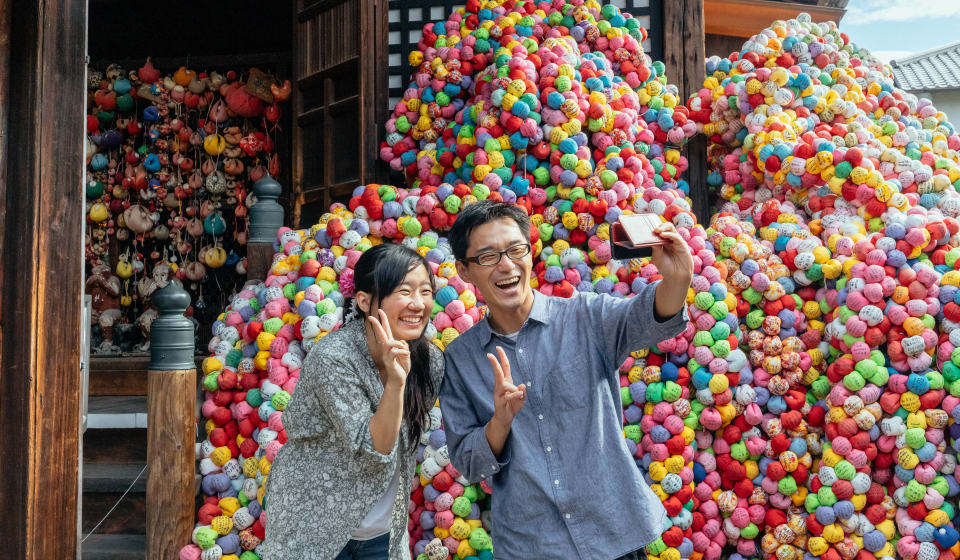 Two travelers taking a picture in Kyoto in front of a very colorful artwork