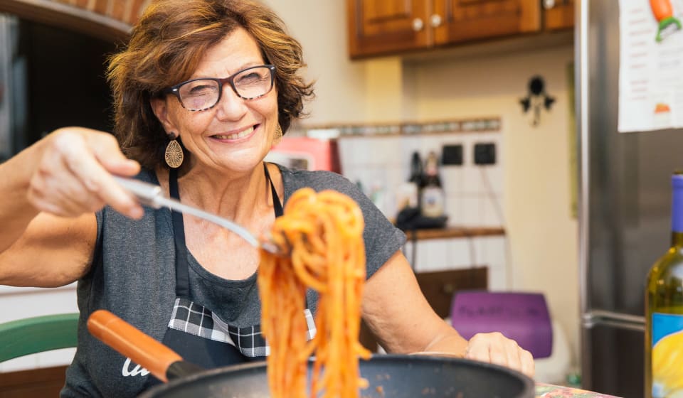 A local guide showing freshly cooked pasta at a home dinner in Rome