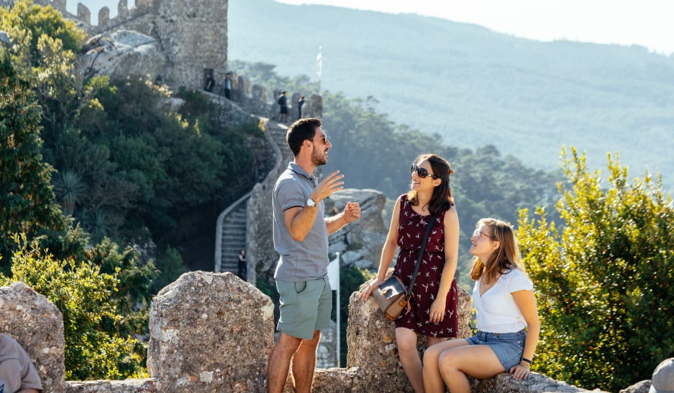 A local guide showing two tourists the beautiful hills and walls of Sintra
