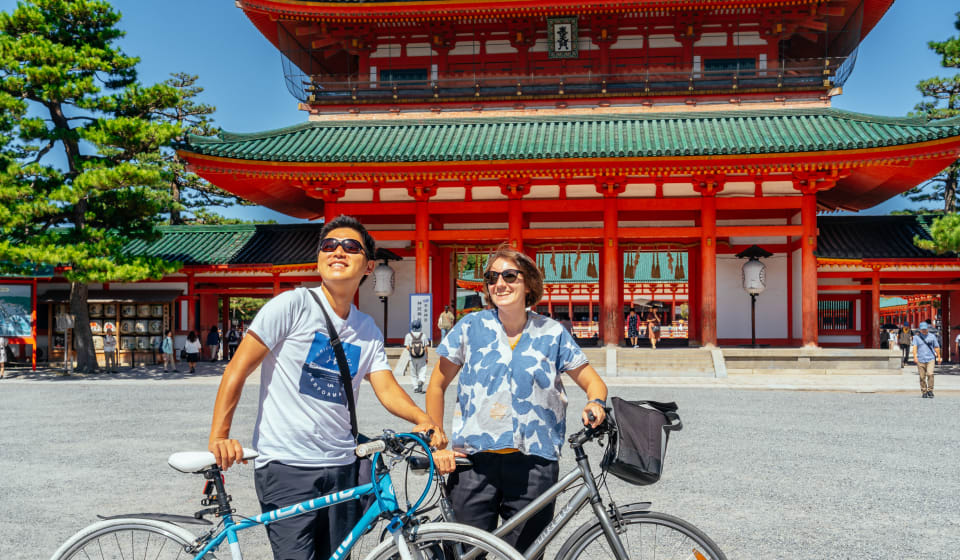 Two tourist with a bike in front of a temple in Kyoto