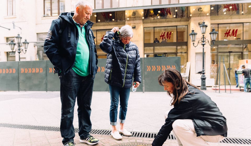 A local guide explaining something on the ground to tourists in Budapest
