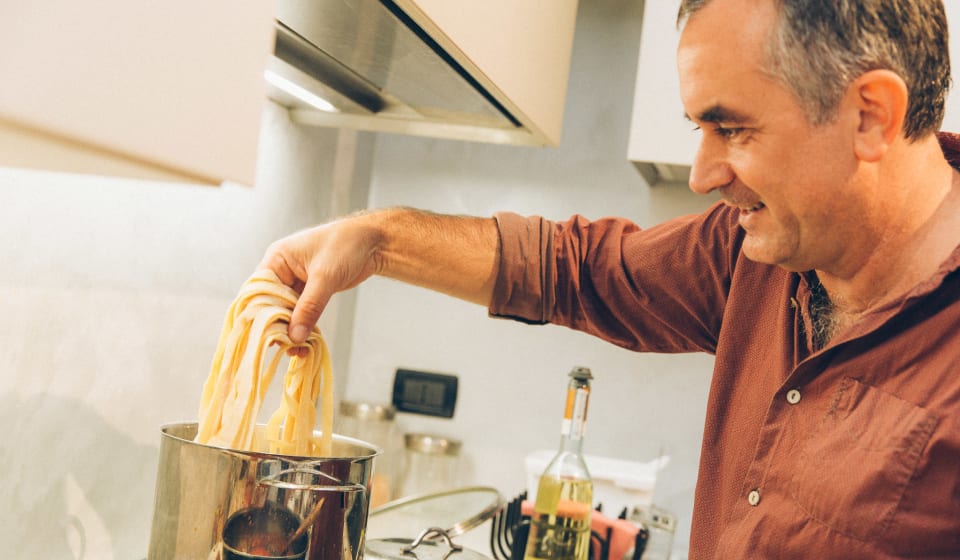 A local guide cooking pasta at a home dinner in Rome