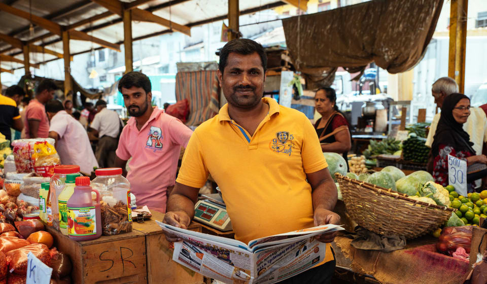 A guy reading the newspaper on a marked in Colombo
