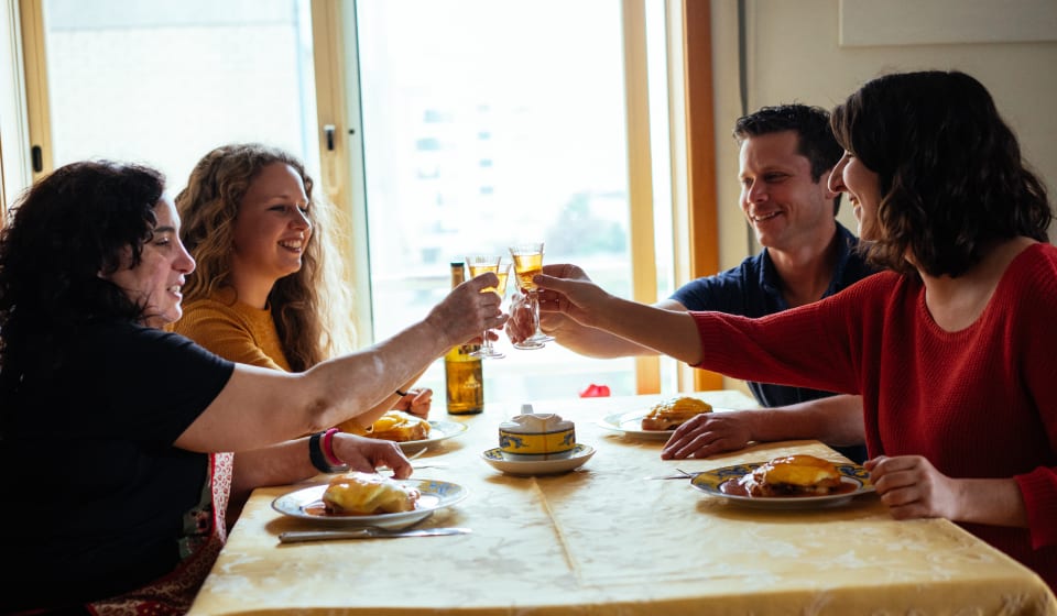 A local and tourists having a toast at a home dinner in Porto