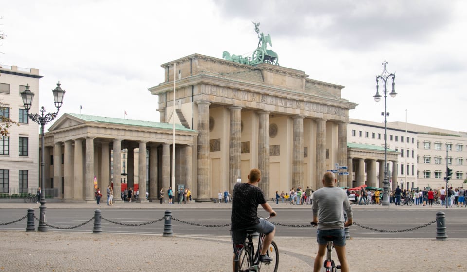 A local guide with a tourist on bikes in front of the Brandenburg gate