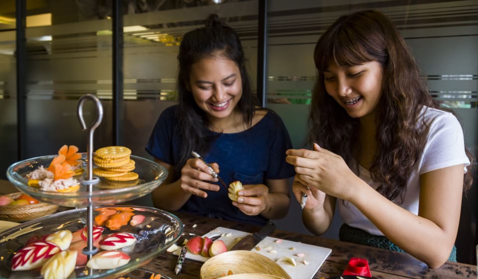 Two tourists doing a workshop of Thai fruit carving in Bangkok