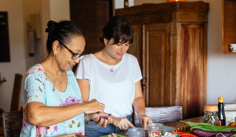 A Balinese local giving a cooking class for a tourist on Bali