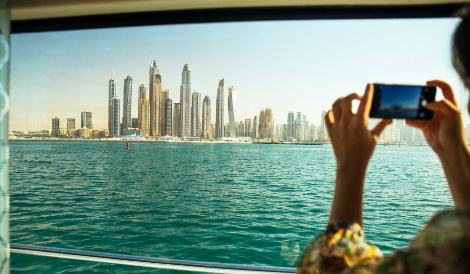 A tourist making a picture of the Dubai skyline form the water