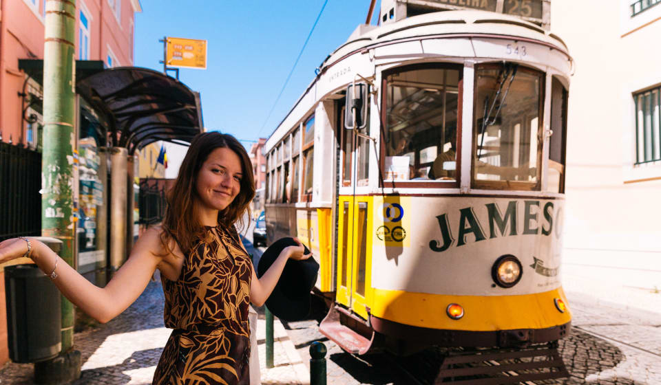 A tourist posing in front of Tram 28 in Lisbon