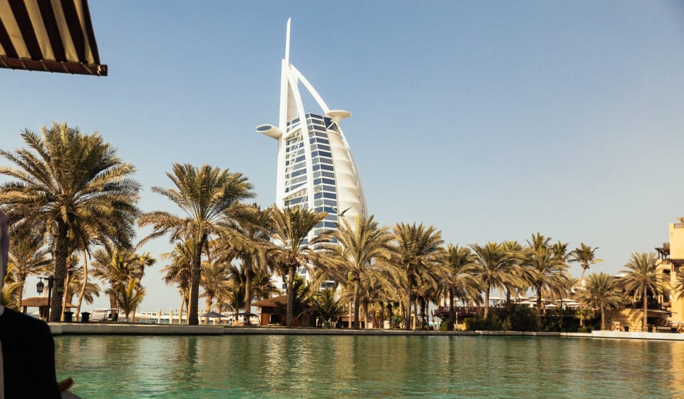 A view from the water to palm trees with the Jumeirah Beach Hotel behind the trees