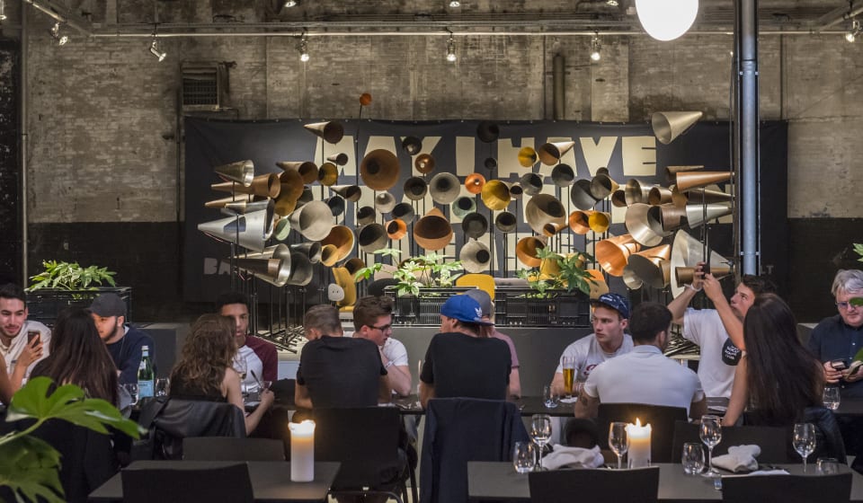 A view of people eating at the Kazerne with an art installation behing them for the Dutch Design Week in Eindhoven