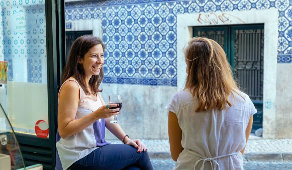 A local guide and a tourist enjoying a port wine and some local food in the streets of Lisbon