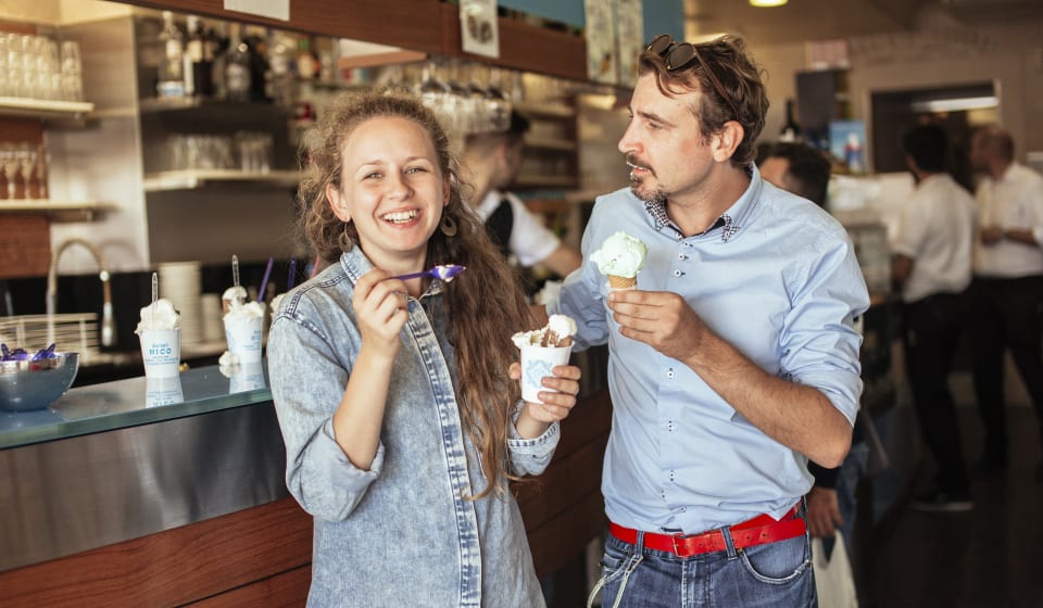A local guide and a tourist laughing while eating an ice cream in Venice
