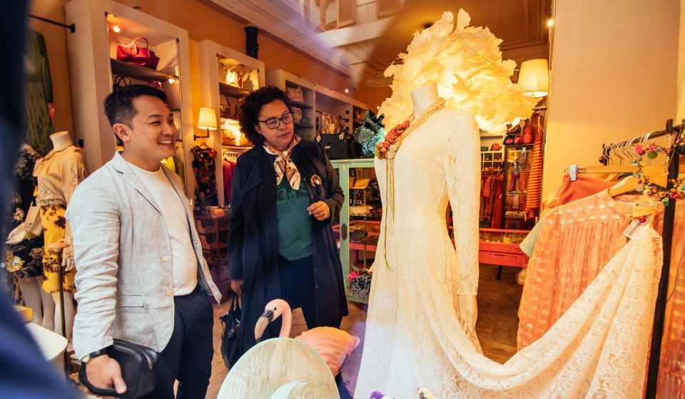 A local guide showing a tourist a white dress in a Milanese fashion shop