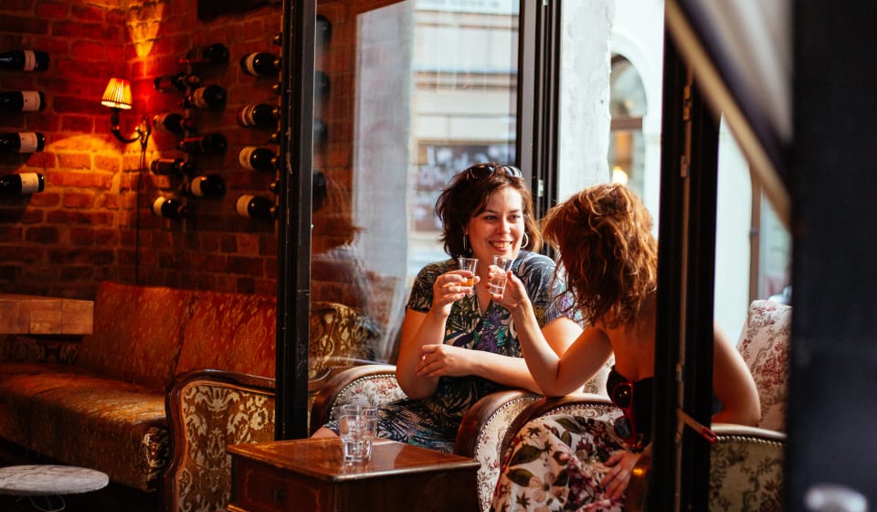 A local guide and a tourist having a toast with a shot in a bar in Belgrade