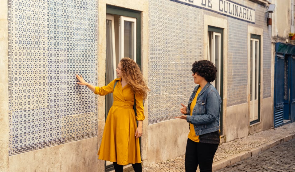 A local guide showing a tourist a building with Portuguese tiles in Lisbon