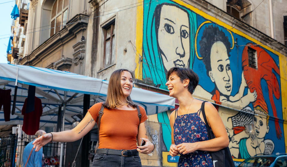 A local guide showing street art to a tourist in Materdei Naples