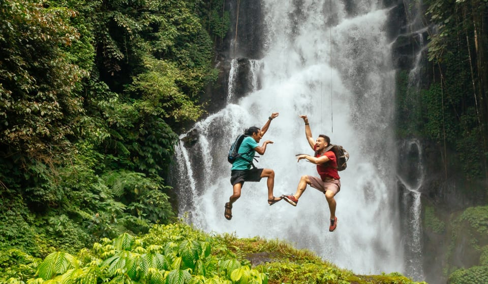 Two people jumping in front of a waterfall on Bali