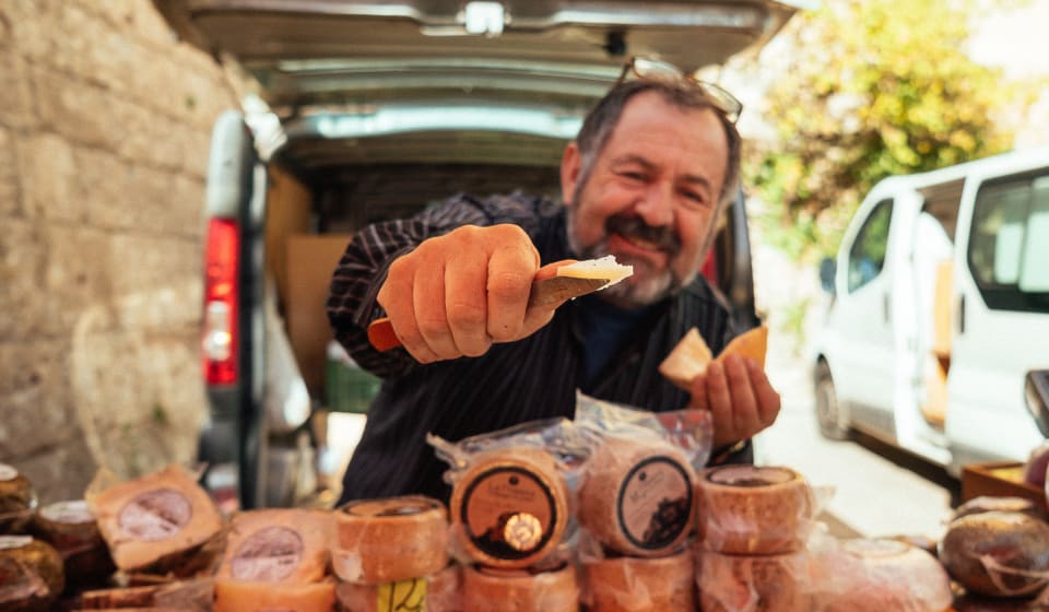 A vendor giving out cheese at the Montserrat market