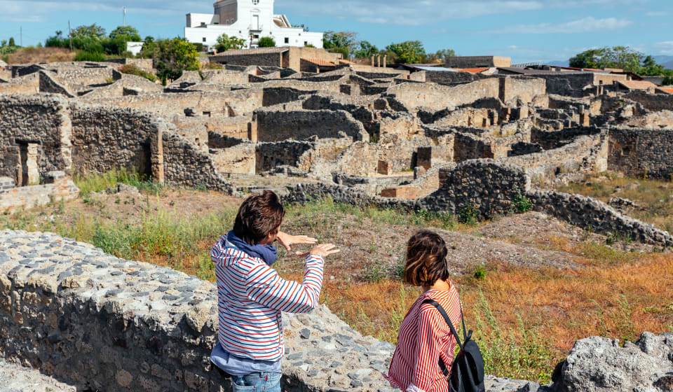 A local guide and a tourist overlooking the some remains of Pompeii