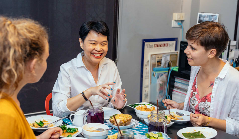 Two tourist and a local having a home dinner in Bangkok