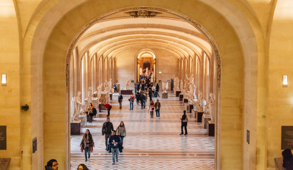 A hallway in the Louvre with a few people