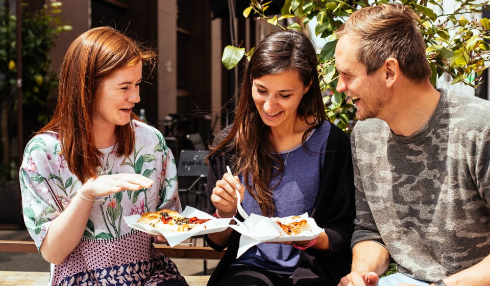 A local guide and two tourist enjoying a tasting of Focaccia in Milan
