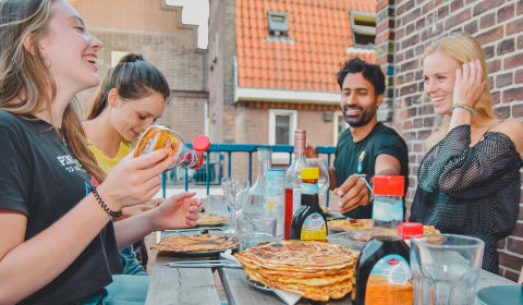 A group of tourists enjoying Dutch pancakes outside on a balcony in Amsterdam