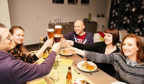 A group sharing dinner and Belgian beers doing a cheer with the beers
