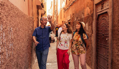 A local guide taking two tourists through the narrow streets of Marrakech