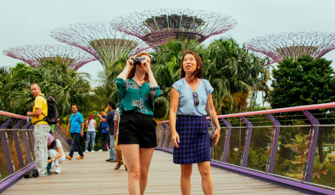 A tourist taking a picture with a local guide on her side in a park of Singapore