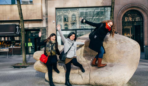 Three tourist posing on a statue in the shape of a hand in Antwerp