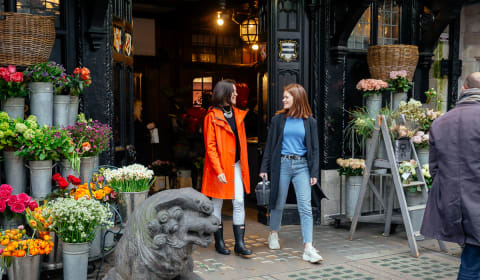 A local guide and a tourist walking at a flower shop in London near the Soho district