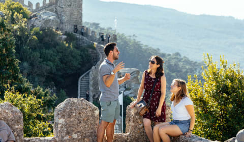 A local guide showing two tourists the beautiful hills and walls of Sintra