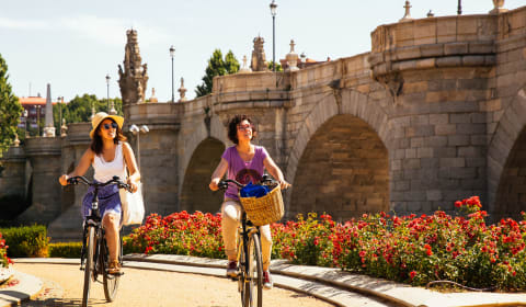 A local guide and tourist cycling through El Retiro park in Madrid
