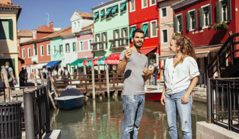 A local guide and a tourist standing near the colorful houses of Murano near Venice