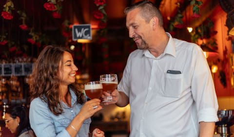 A man and a woman cheering with a beer in a pub