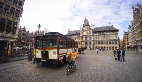 Old bus and a woman cycling next to it at Plein Publiek in Antwerp