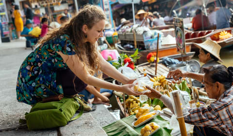 A tourist buying fresh produce from the Floating Market in Bangkok, Thailand