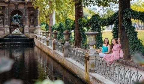Two locals in one of the gardens of Paris sitting on a bench at a water pont