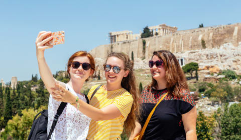 A group of tourists making a selfie with the Acropolis at the background in Athens