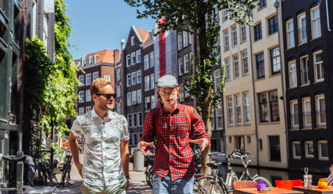 A local showing a tourists a street in Amsterdam next to a canal