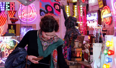 A tourist surrounded by all the light signs in God's Own Junkyard in Walthamstow, London