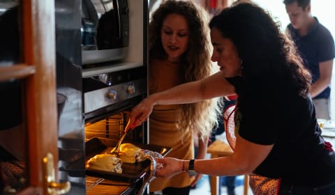 A local showing to a tourist how to make Francesinha at a home dinner cooking workshop in Porto